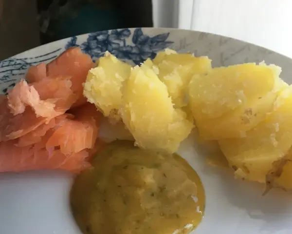 En tallrik med gravad lax, kokt potatis och en klick gravlaxsås. Perfekt för ett snabbt och gott recept.