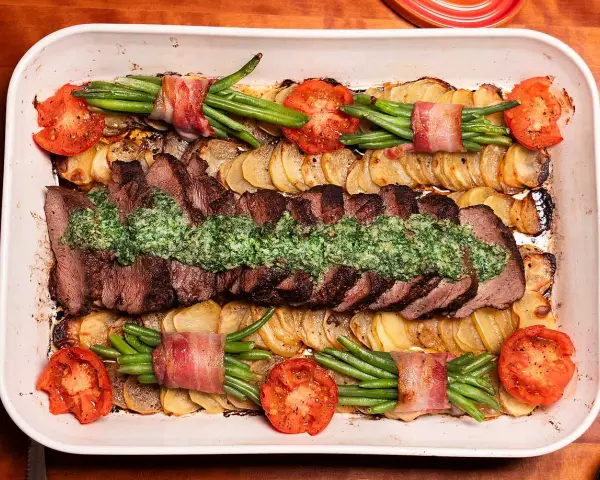 En saftig coeur de filet provencale med potatis, gröna bönor inslagna i bacon och tomater i en ugnsform.