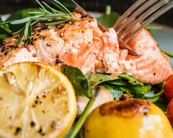 En saftig bit inkokt lax i ugn, serverad med citron, körsbärstomater och färska örter. En härlig måltid!