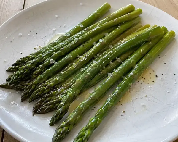 En tallrik med nykokt sparris, lätt oljad och strödd med flingsalt och peppar. Perfekt för att koka sparris till en enkel och god rätt.