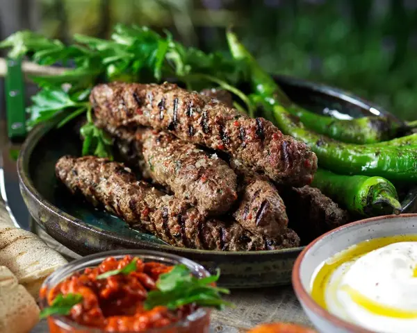 Grillade cevapcici med gröna paprikor, persilja, pitabröd och en röd röra. Ett perfekt cevapcici recept för sommaren.