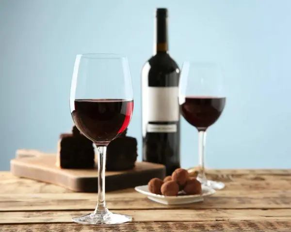 Två glas rött vin, en flaska, chokladpraliner och en bit chokladkaka. En perfekt kombination av vin till choklad.