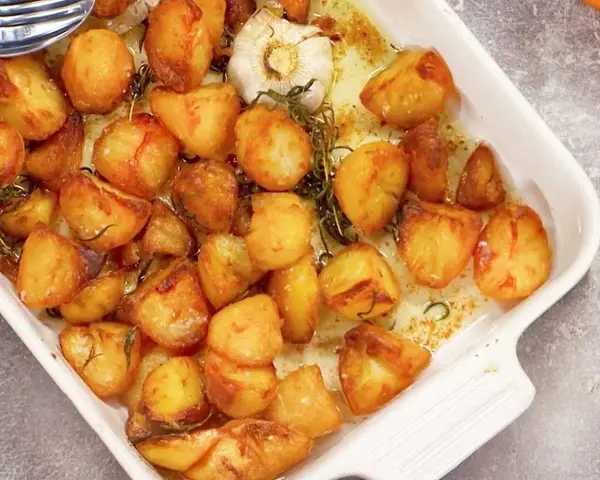 Ugnsrostad potatis med vitlök och rosmarin i en vit ugnsform. Perfekt tillbehör som doftar ljuvligt!