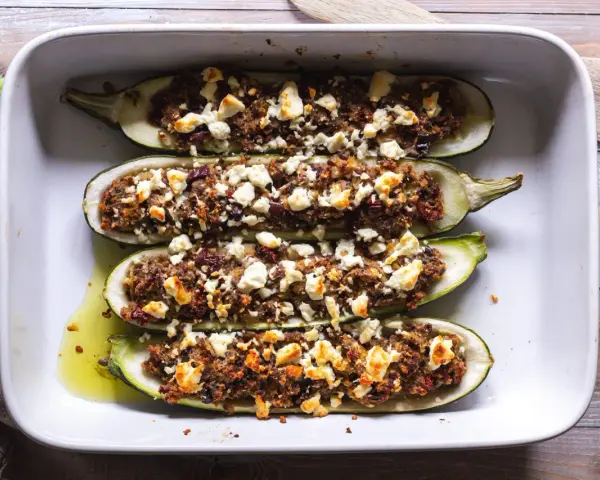 Ugnsbakade zucchinihalvor fyllda med en smakrik blandning och toppade med smulad fetaost. En härlig rätt med zucchini i ugn med fetaost.