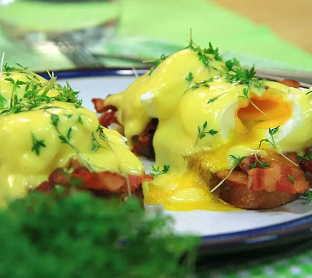 Läckra eggs benedict med krämig hollandaisesås, knaprigt bacon och färska örter. En perfekt start på dagen!