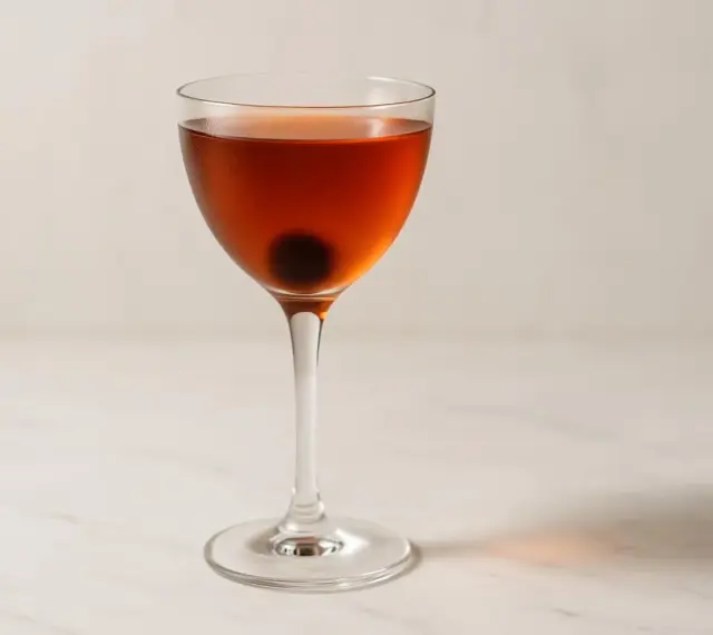 En klassisk manhattan drink med körsbär i ett elegant glas.