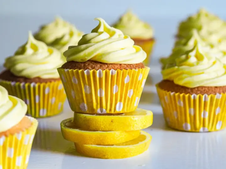 Gula citronmuffins med fluffig frosting, serverade i prickiga formar. Perfekt för ett citronmuffins recept!