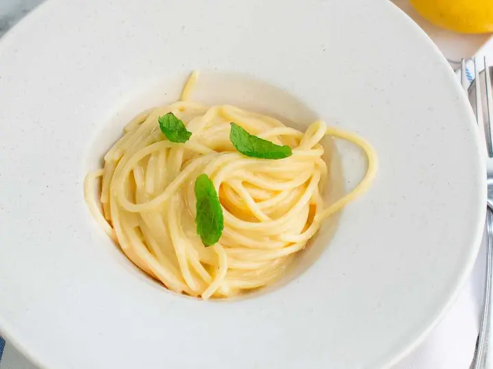 En krämig pasta limone, serverad i en vit skål med färska myntablad.