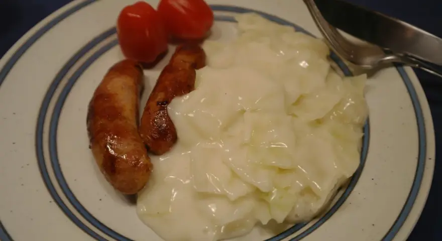 En tallrik med stuvad vitkål, korv och tomater. En klassisk svensk husmanskosträtt.