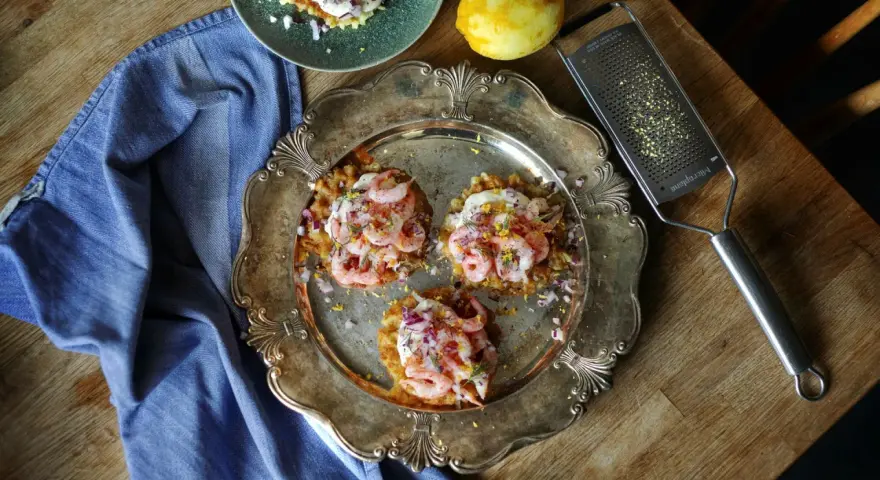 Tre potatisbullar med räkor, rödlök och dill på en silverbricka. Ett recept på potatisbullar som ser utsökt ut!
