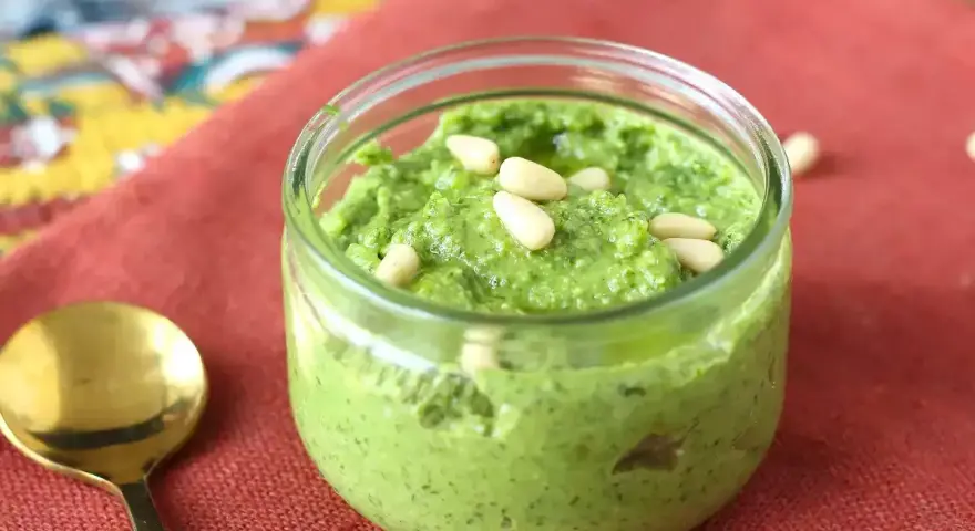 En burk med hemgjord pesto, toppad med pinjenötter. Perfekt för ditt nästa pesto recept!