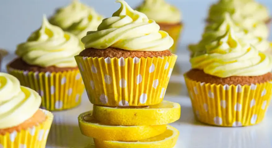 Gula citronmuffins med fluffig frosting, serverade i prickiga formar. Perfekt för ett citronmuffins recept!