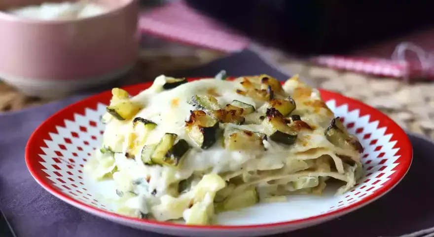 En bit krämig vegetarisk lasagne med zucchini, toppad med gyllene ost och grönsaker.
