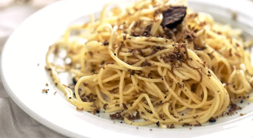En tallrik med spaghetti toppad med rikligt med riven tryffel. Perfekt för en lyxig middag med ett gott vin till tryffelpasta.