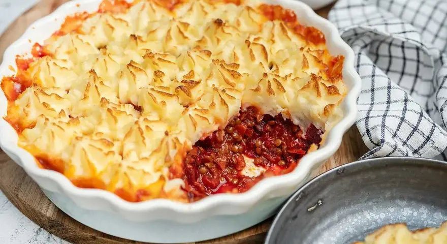 En gyllene shepherd's pie med potatismoslock, fylld med en mustig lins- och rotfruktsröra. Serveras med rödbetor.