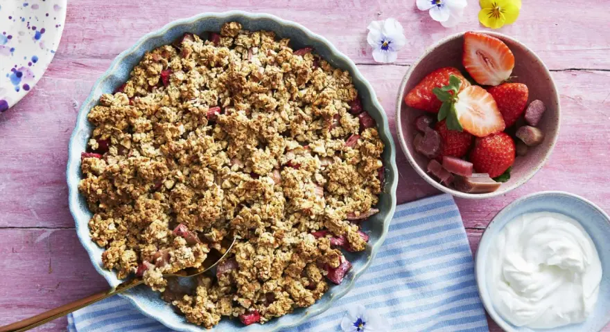 En härlig gammaldags rabarberpaj med krispigt täcke, serverad med färska jordgubbar och grädde. Perfekt sommardessert!