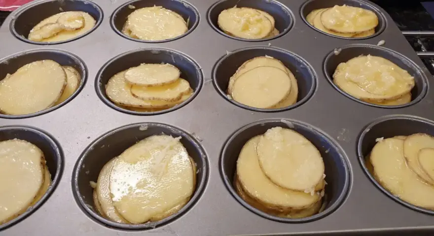 Tunna skivor av potatis i muffinsform, redo att bakas. Enkel och god rätt.