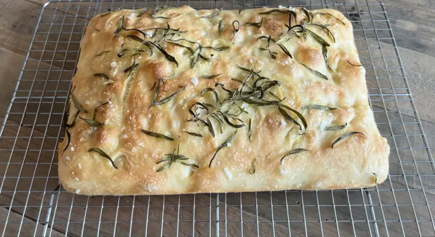 En gyllene, nybakad focaccia med rosmarin och flingsalt, perfekt för ditt nästa focaccia recept.