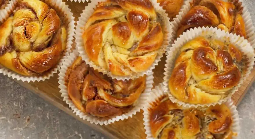 Nybakade bullar med mandelmassa och vallmofrön, gyllene och glansiga i sina pappersformar.