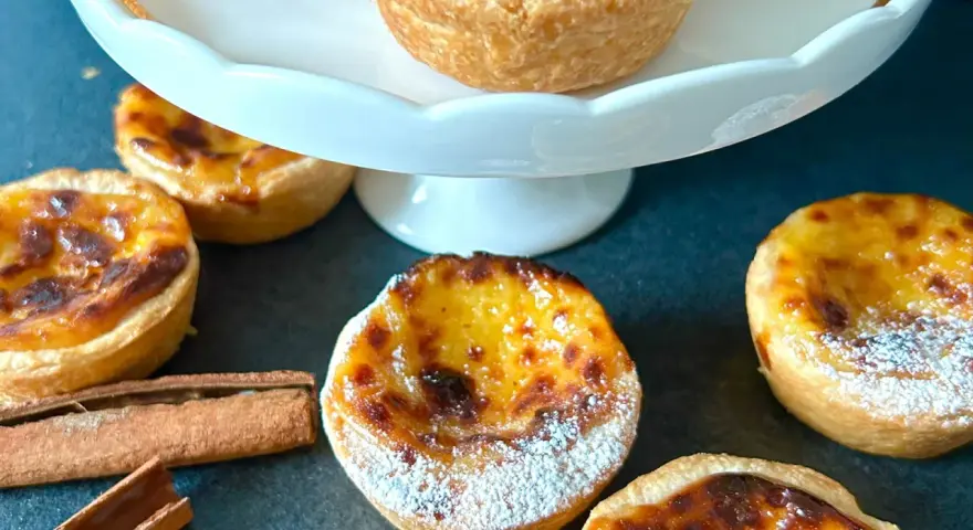 Fluffiga, gyllene pastel de nata med pudersocker och kanelstänger. En härlig fika!