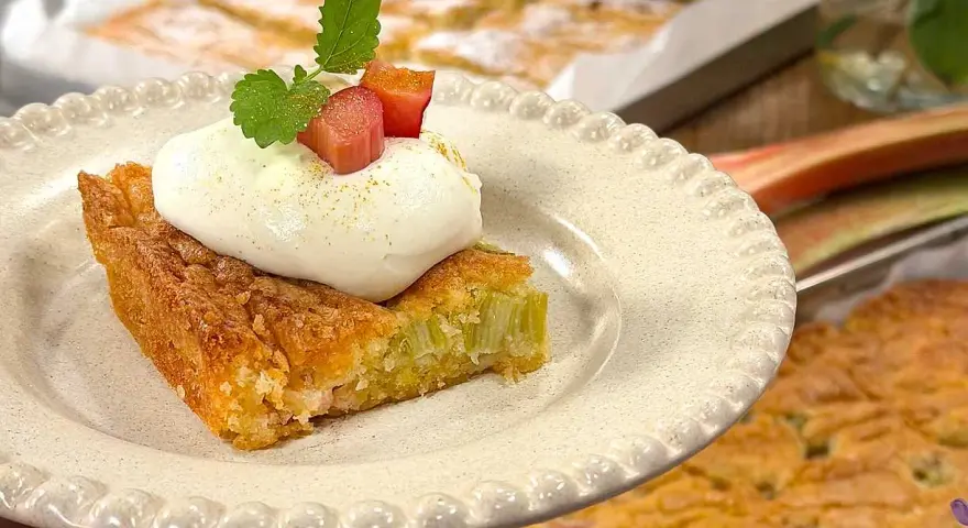 En saftig rabarberkaka i långpanna, toppad med fluffig grädde och färska myntablad. Perfekt för fika!