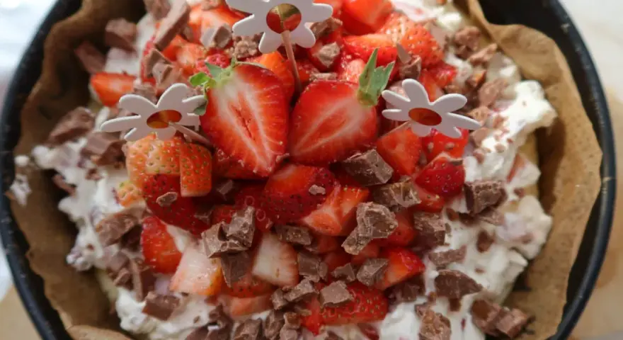 En läcker cheesecake med jordgubbar och chokladbitar, perfekt för ett somrigt cheesecake recept. Blomsterpinnar dekorerar toppen.