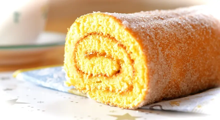 En sockerströdd rulltårta med marmeladfyllning, perfekt för ett enkelt rulltårta recept.