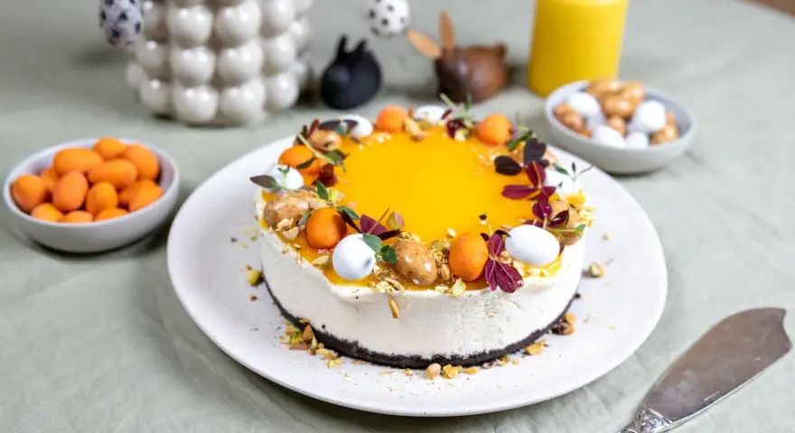 En vacker cheesecake med gul topping, dekorerad med påskägg och nötter. Perfekt för en härlig cheesecake påsk-firande.