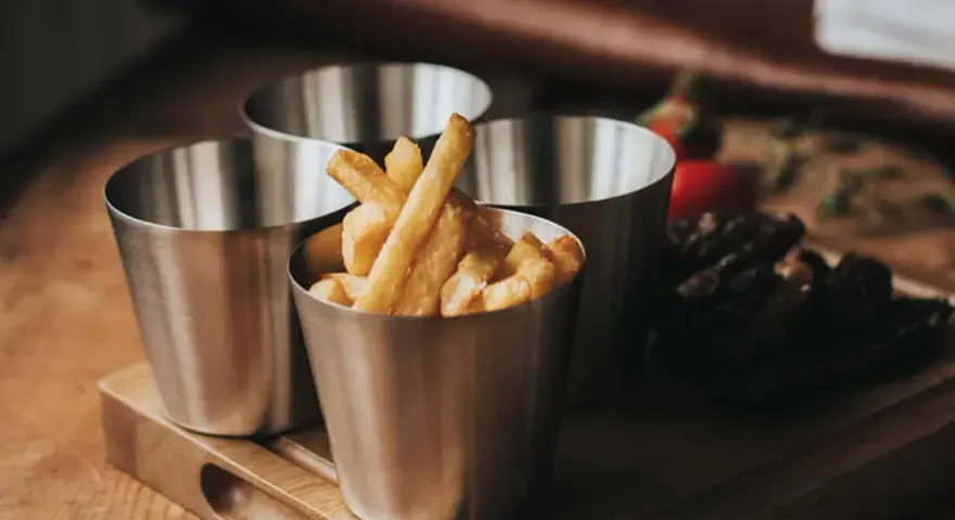 Friterade pommes i kastrull, serverade i små metallmuggar. En läcker aptitretare som påminner om hemgjord snabbmat.