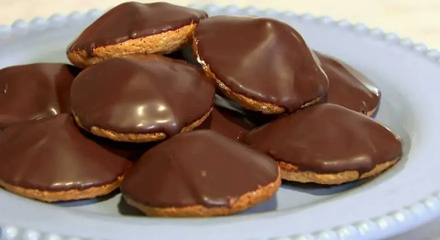En hög med chokladöverdragna biskvier på en ljusblå tallrik. Perfekt för ett enkelt biskvier recept.