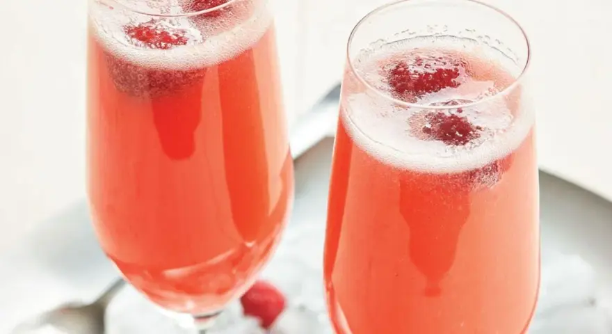 Två glas med ett rosa drink med bubbel och hallon. Perfekt för en festlig stund.