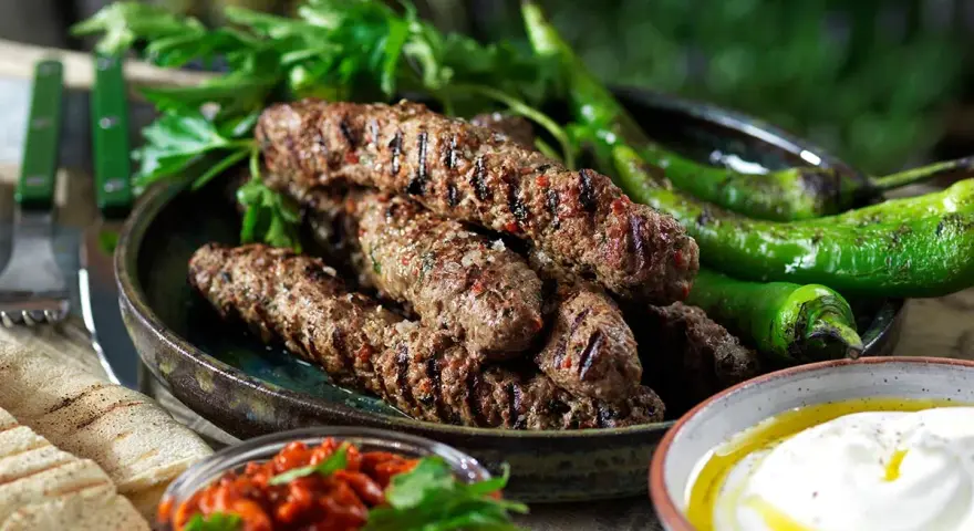 Grillade cevapcici med gröna paprikor, persilja, pitabröd och en röd röra. Ett perfekt cevapcici recept för sommaren.