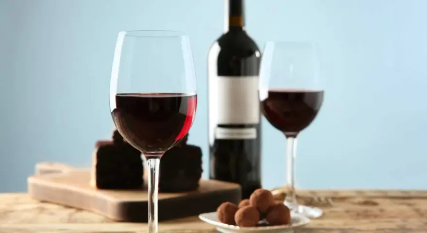 Två glas rött vin, en flaska, chokladpraliner och en bit chokladkaka. En perfekt kombination av vin till choklad.