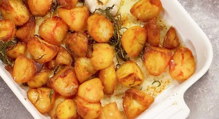 Ugnsrostad potatis med vitlök och rosmarin i en vit ugnsform. Perfekt tillbehör som doftar ljuvligt!