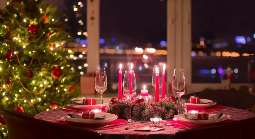 Ett dukat bord med julgran och tända ljus, redo för ett härligt vin till julbordet.