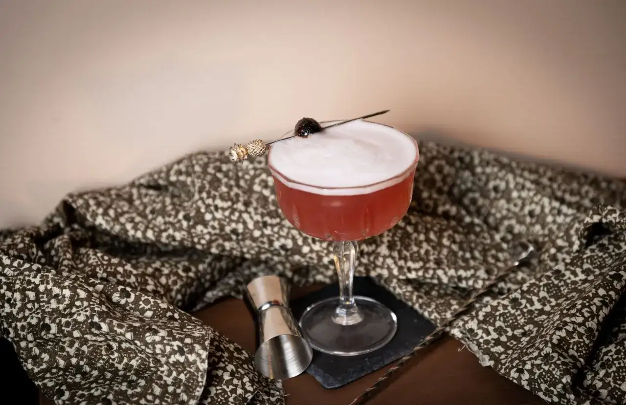 En elegant pink lady drink med skum och körsbärsgarnityr, redo att avnjutas.