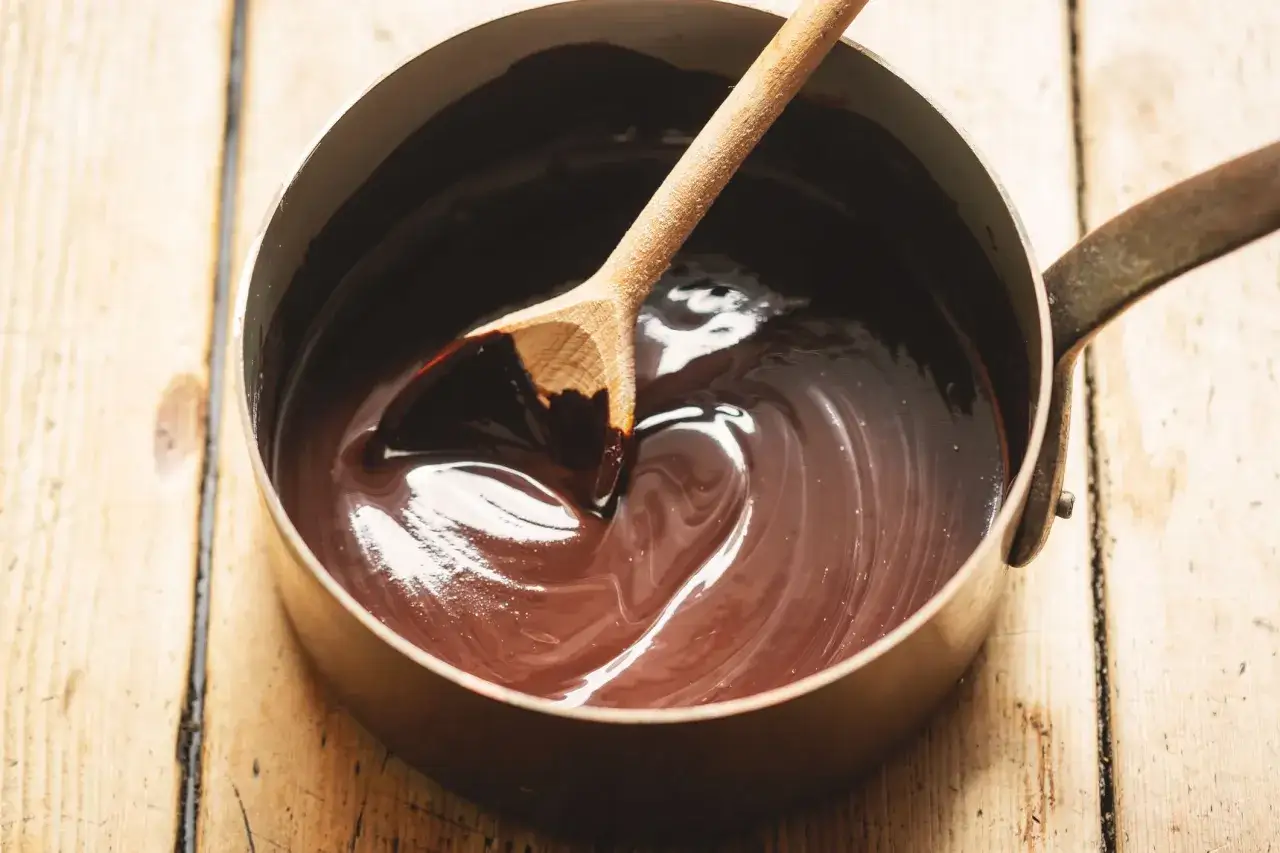 En kastrull med glansig choklads&aring;s och en tr&auml;sked. Perfekt f&ouml;r ditt choklads&aring;s recept.