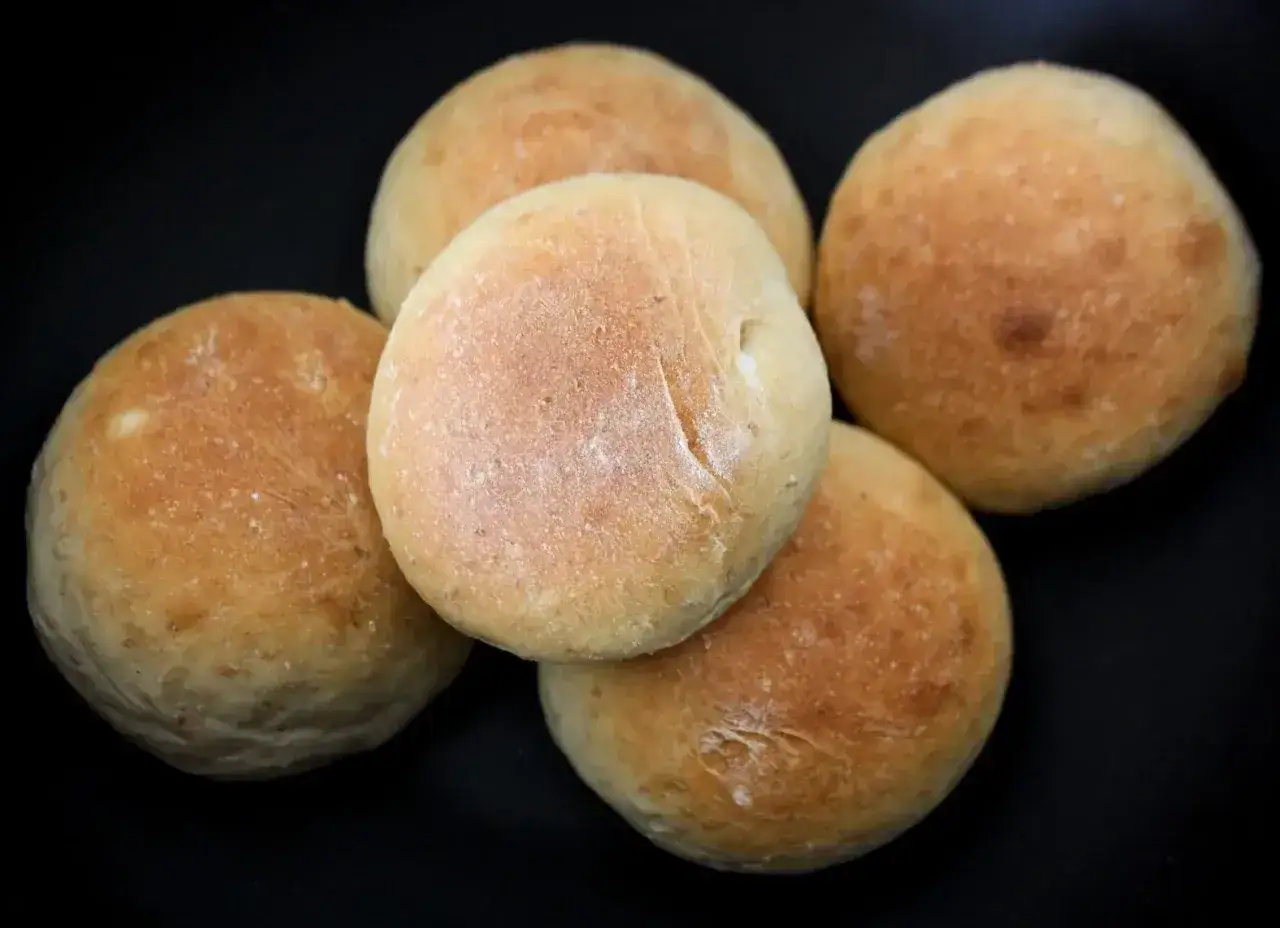 Fem nybakade frallor på en mörk bakgrund. Perfekt för ett enkelt frallor recept.