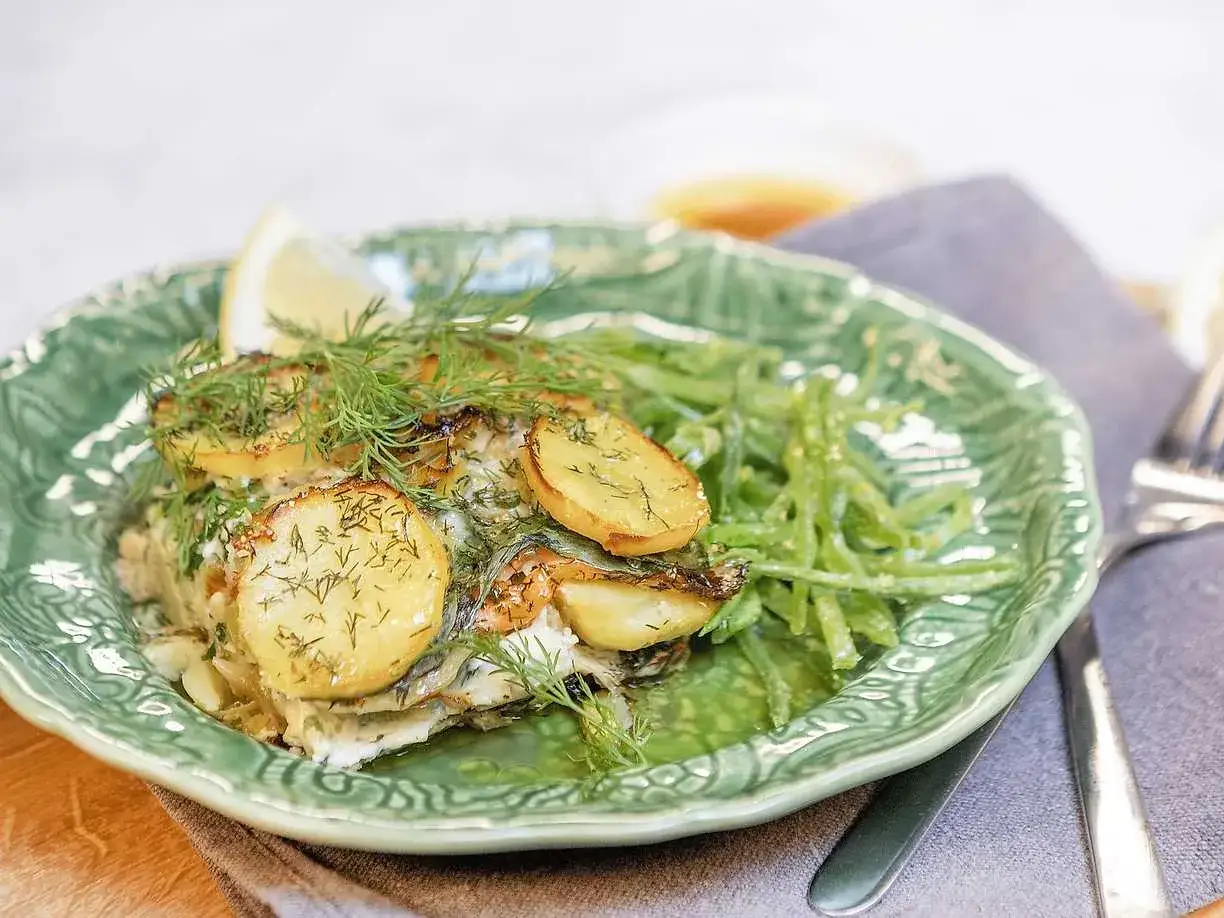 Laxpudding recept med potatis, dill och gröna bönor på en grön tallrik. En citronskiva toppar rätten.