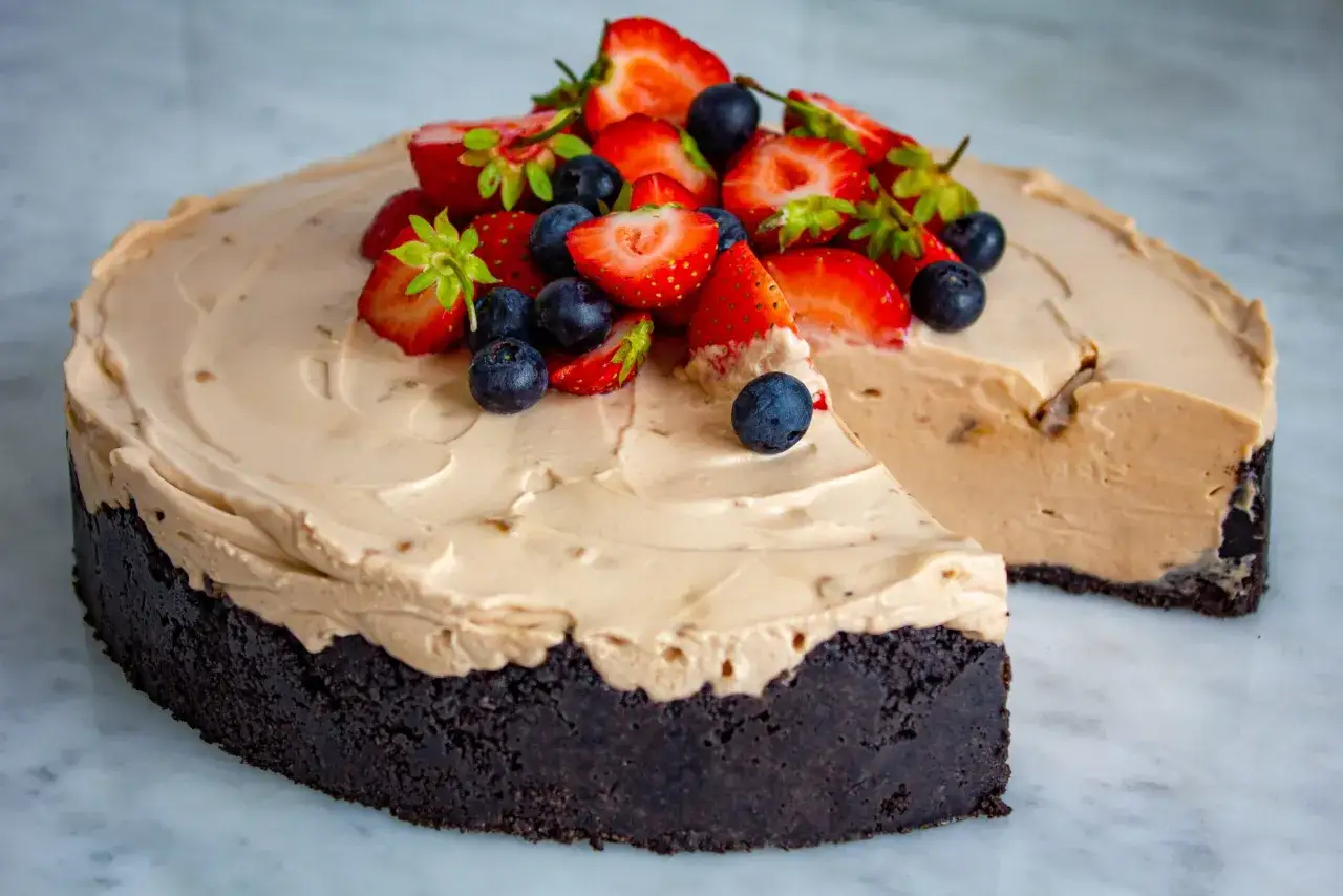 En krämig daim cheesecake med chokladbotten, toppad med färska jordgubbar och blåbär. En dröm för alla som älskar sött!