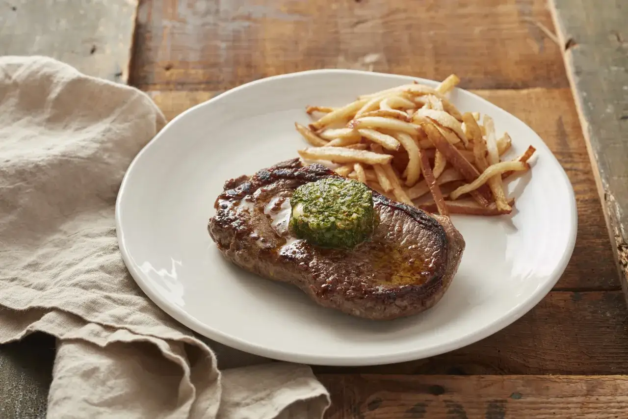 En saftig biff med pommes frites och en klick cafe de paris sås som smälter över köttet.