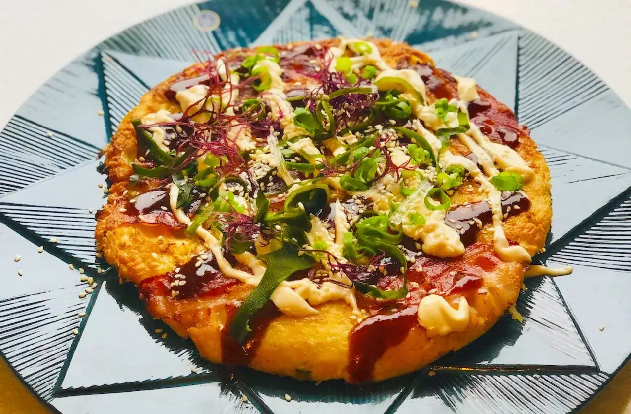 En läcker okonomiyaki med strimlade grönsaker, majonnäs och sås. Ett perfekt recept för en smakrik måltid.