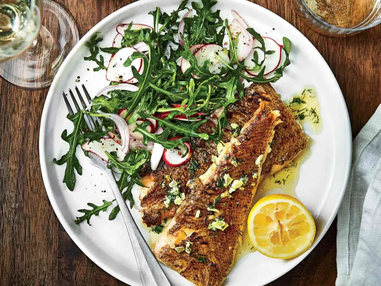 Perfekt grillad fisk med en fräsch sallad på ruccola, rädisor och rödlök. En citronskiva fulländar denna somriga rätt.