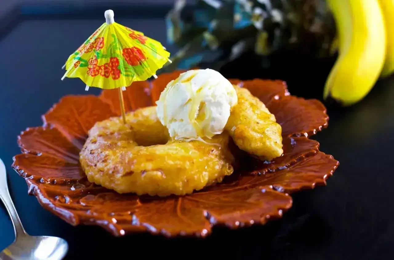Friterad banan med vaniljglass och en liten gul parasoll. En läcker dessert som ser ut att vara från en tropisk semester.