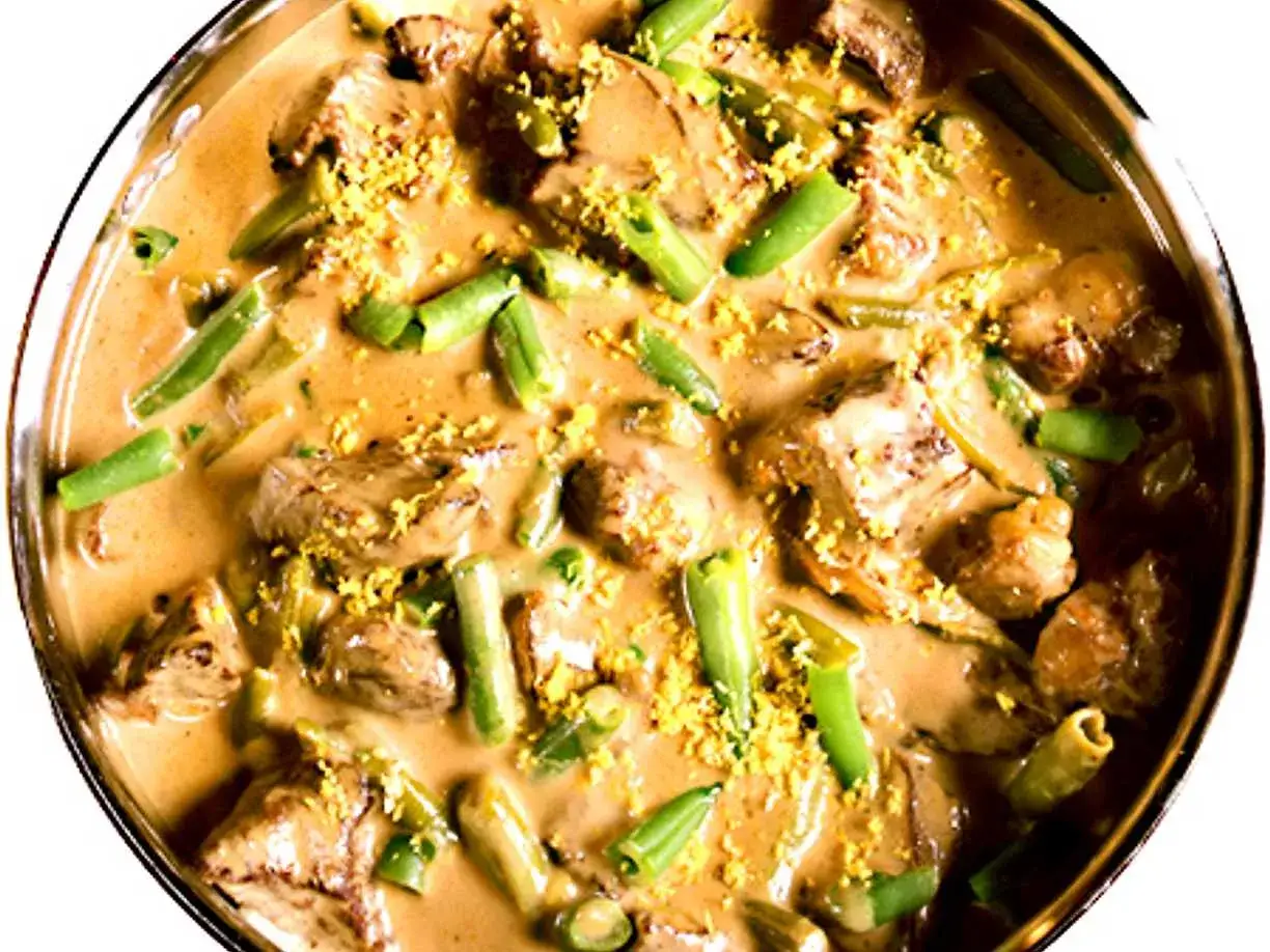 En krämig biff stroganoff med möra köttbitar och gröna bönor, toppad med gul strössel.