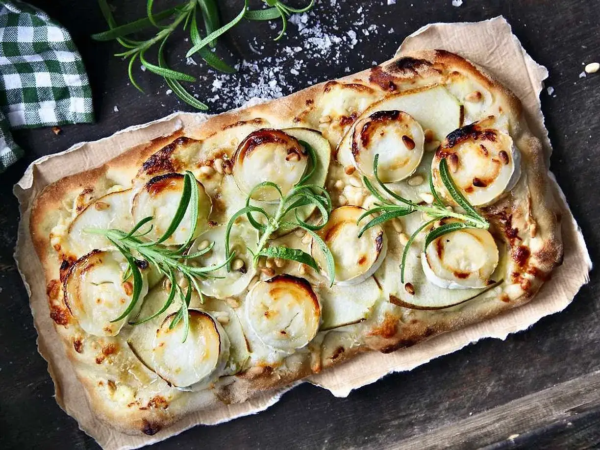 En läcker pinsa med chevre, tunna potatisskivor och rosmarin, toppad med pinjenötter och flingsalt.
