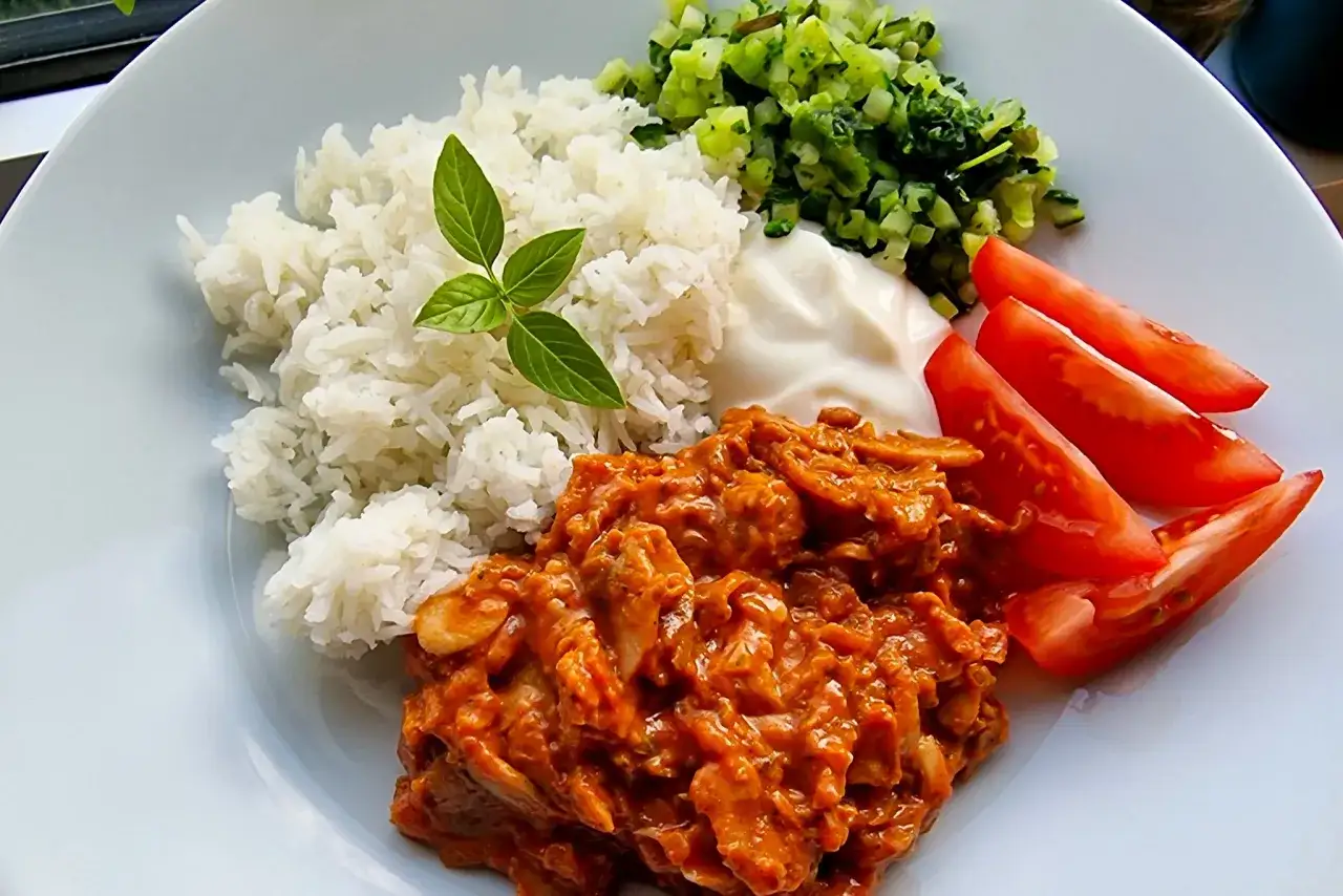 En smakrik kebabgryta med ris, serverad med fräscha tomater och en klick vit sås. En perfekt middag!