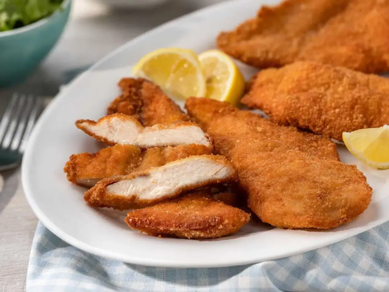 Krispig kyckling i airfryer serverad med citronklyftor på en vit tallrik. Perfekt för en snabb och god middag.