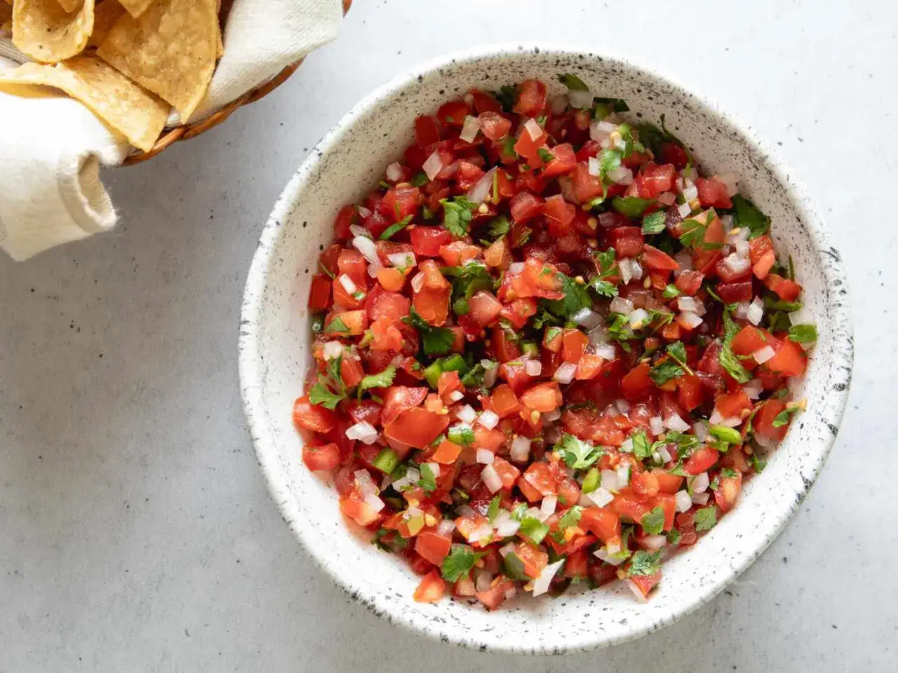 En sk&aring;l med f&auml;rsk pico de gallo, full av tomater, l&ouml;k och koriander, redo att serveras med tortillachips.
