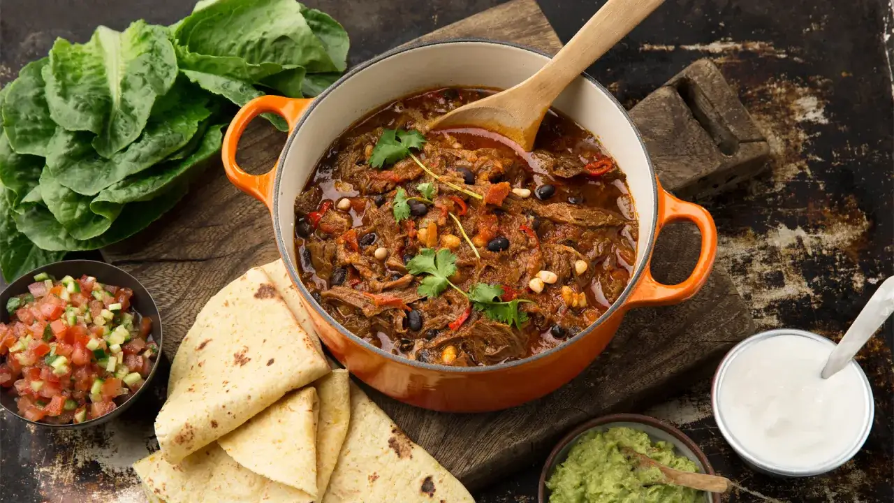 En mustig chili con carne i orange gryta, serverad med tortillabröd, salsa, guacamole och gräddfil.